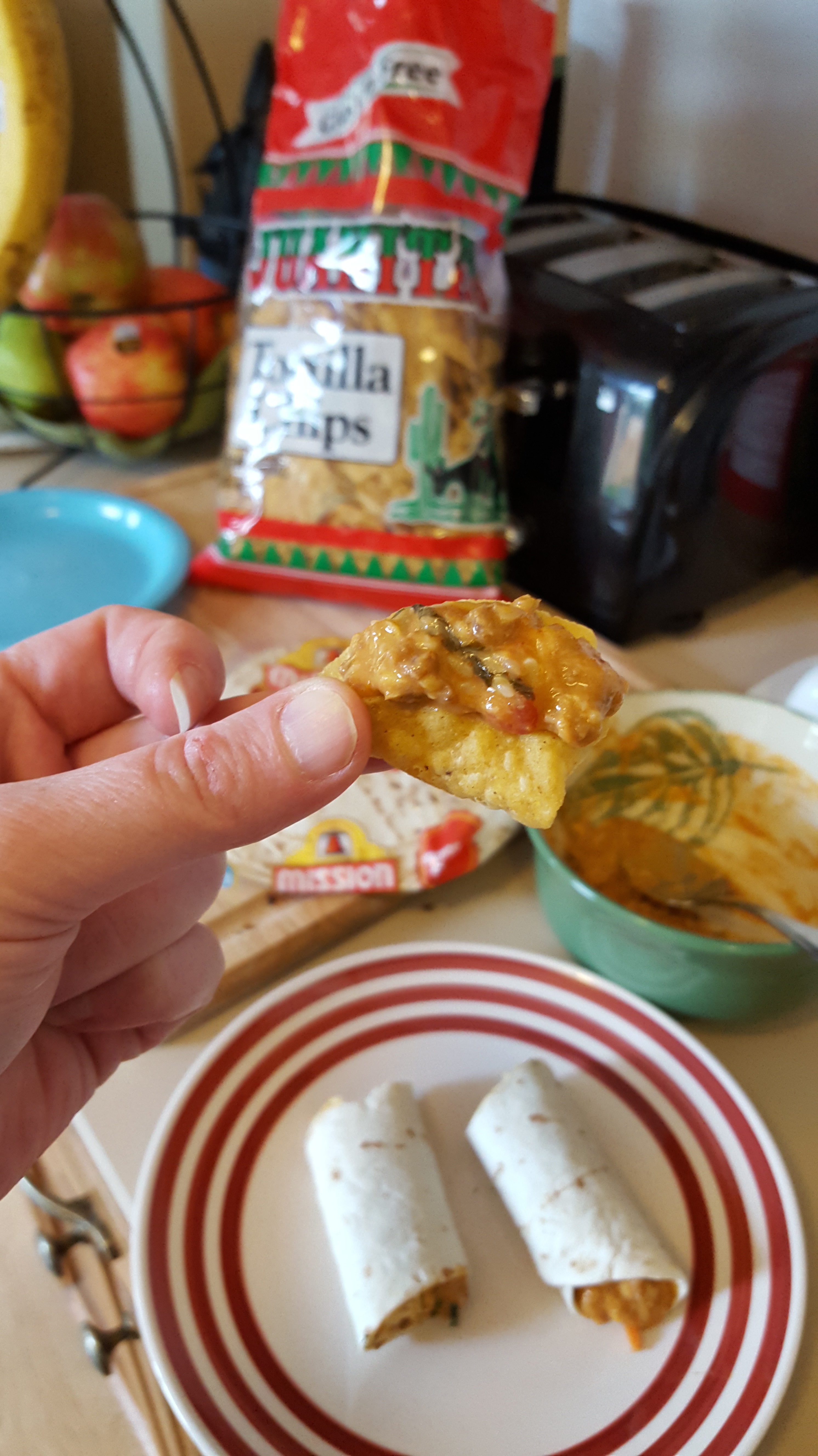 Hand holding tortilla chip with dip
